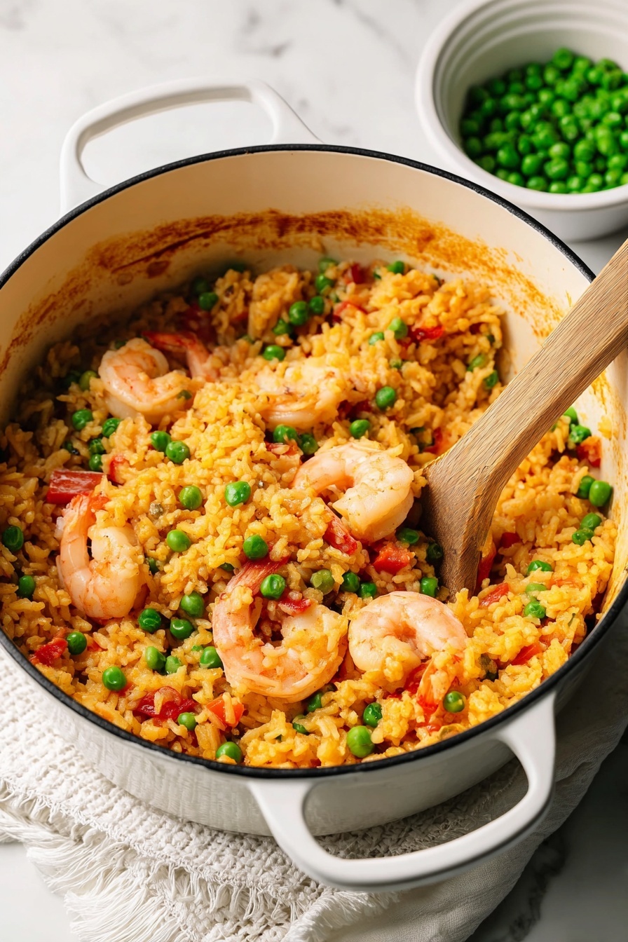 A white pot filled with cooked yellow-orange rice mixed with bright green peas, pink shrimp with tails, and small pieces of red bell pepper. The inside rim of the pot shows a brownish residue from cooking. A wooden spoon is partially buried in the rice on the right side. In the background, there is a small white bowl filled with green peas. The pot is placed on a folded white cloth with textured edges, all on a white marbled surface. photo taken with an iphone --ar 2:3 --v 7