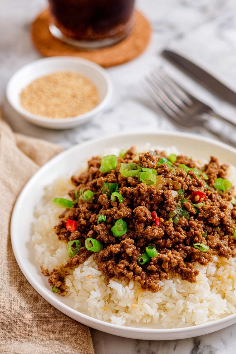 A frying pan with cooked ground meat simmering in a rich, reddish-brown sauce with visible small chunks of tomatoes, surrounded by steam rising from the hot food. The pan is dark gray with a slightly rough texture, sitting on a stove burner with black grates. The stew-like mixture has a thick, moist texture with bits of meat and sauce evenly spread over the entire surface. photo taken with an iphone --ar 2:3 --v 7
