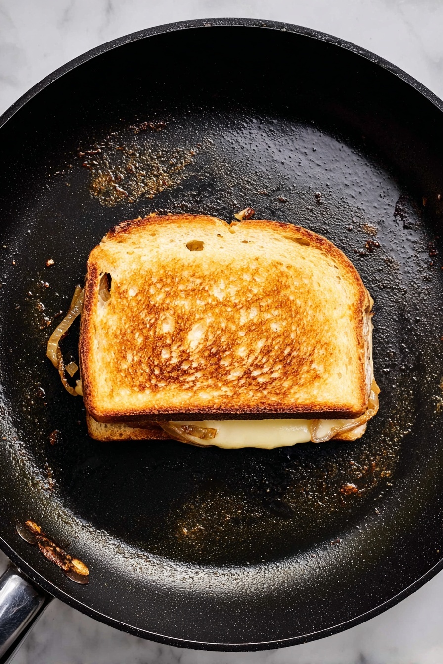 A grilled sandwich is cut in half and placed in the center of a white plate with a textured metal look. The sandwich has three layers: the outer layer is toasted dark brown bread with grill marks, the middle layer shows a cooked beef patty with a slightly pink center, and melting light cheese under the beef, topped with soft cooked onions that have a pale golden color. The sandwich halves are surrounded by many ridged potato chips, which are golden yellow with some green herb bits sprinkled over everything. Photo taken with an iphone --ar 2:3 --v 7